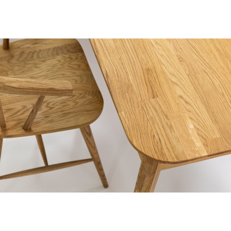 Lähikuvassa on luonnonvärisen Vera-tammipöydän pyöristettykulmaista kannen pintaa  kuvattuna erikseen myytävän Aida-tammituolin kanssa.