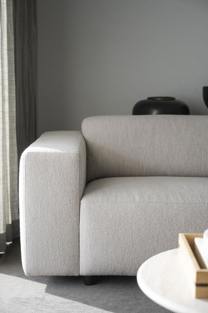 Kuvassa on neljän istuttava Willard-divaanisohva vaaleanbeigellä Alice 01 -kankaalla ja mustilla muovijaloilla.