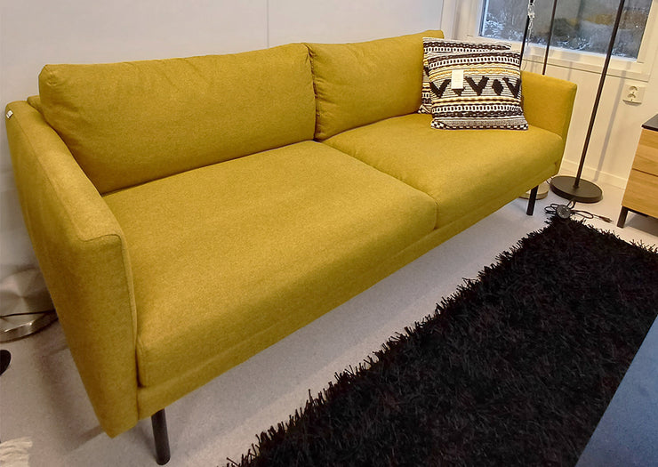 Kuvassa on  3-istuttava Malmö-sohva okran värisellä Modena 41 -kankaalla kuvattuna myymälämiljöössä. Kuvan muut tuotteet, kuten matto ja Mattokympin  Hulda-koristetyyny myydään erikseen.