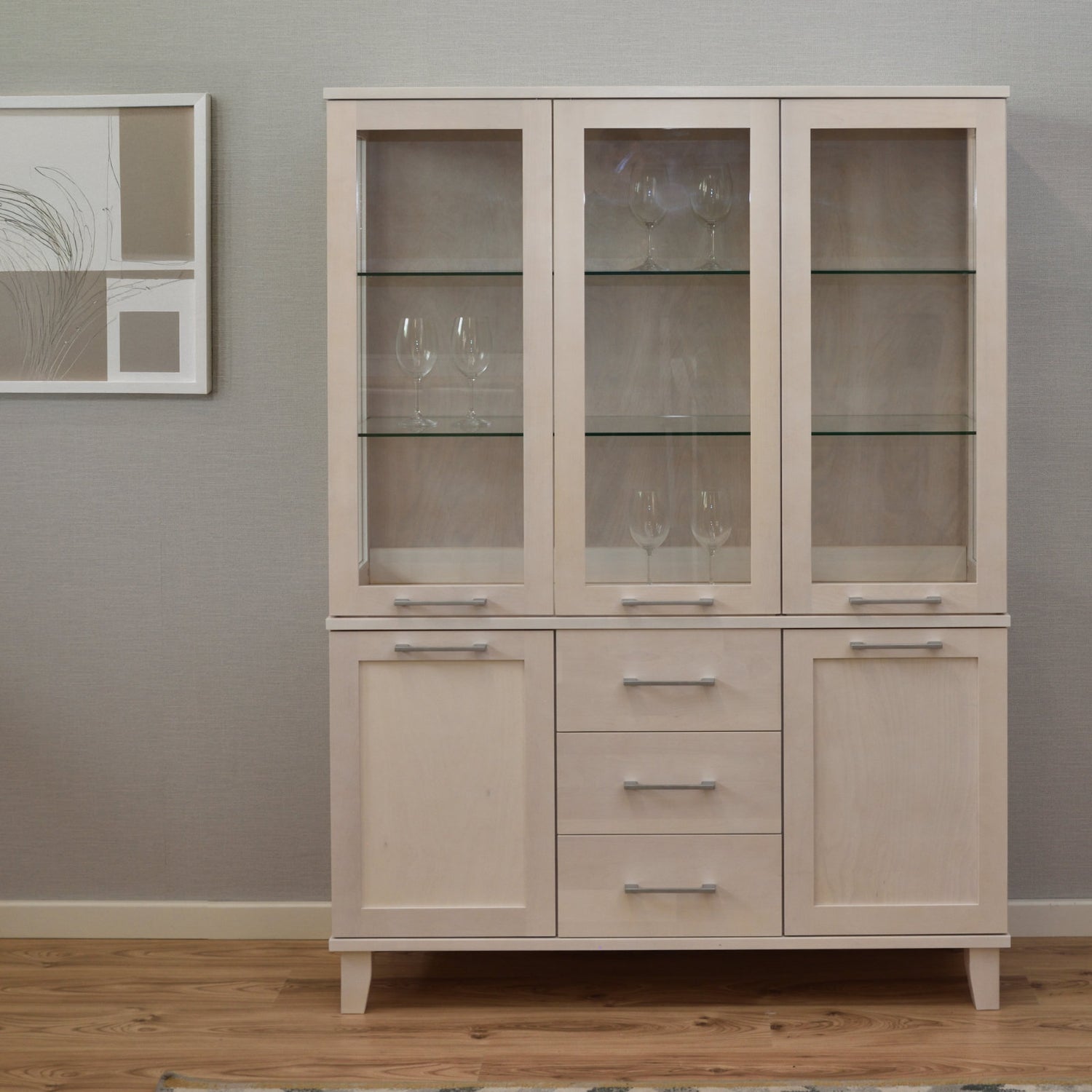 Kuvassa on kuultovalkoinen Vuokatti-vitriini. Vitriinissä on lasikaapisto lasihyllyillä, alaosan tilava senkki kaappien peiliovilla, sekä pitkänmalliset RST-vetimet. Lasikaapin sisällä olevat viinilasit eivät kuulu hintaan.