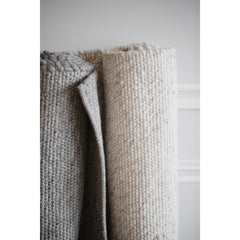 Harmaa ja luonnonvalkoinen Ackland-villamatto kerälle rullattuna.