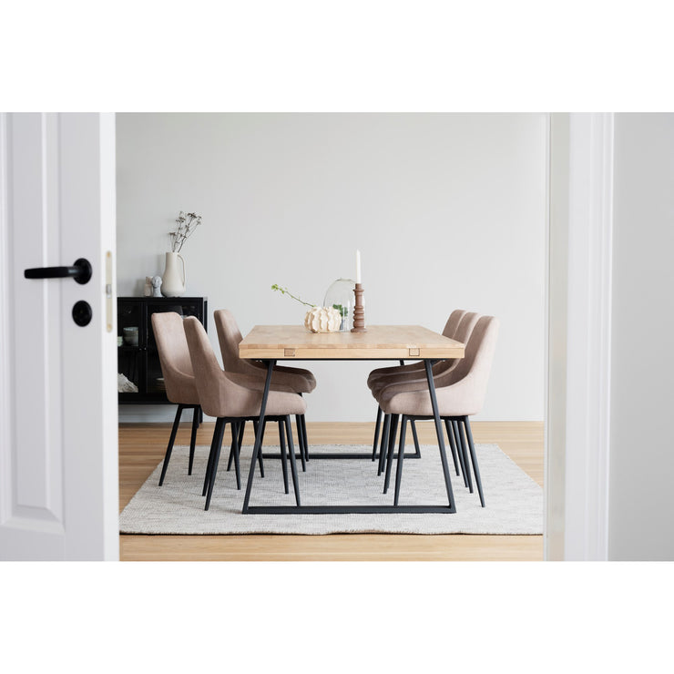 Kuvassa on tammenvärinen ruokaryhmä 220 x 95 cm Brooklyn-ruokapöydällä, jossa on U-malliset mustat metallijalat. Kuuden hengen ruokaryhmän tuoleina on erikseen myytävät Rowicon beigenväriset Sierra-tuolit.