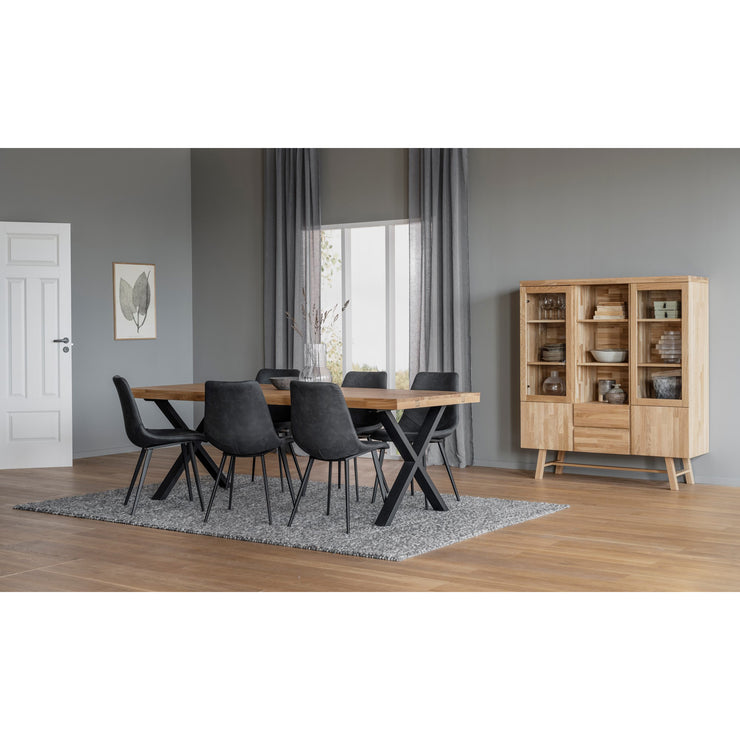 Kuvassa on tammenvärinen ruokaryhmä 220 x 95 cm Brooklyn-ruokapöydällä, jossa on X-malliset mustat metallijalat. Kuuden hengen ruokaryhmän tuoleina on erikseen myytävät Rowicon mustat Sierra-tuolit.