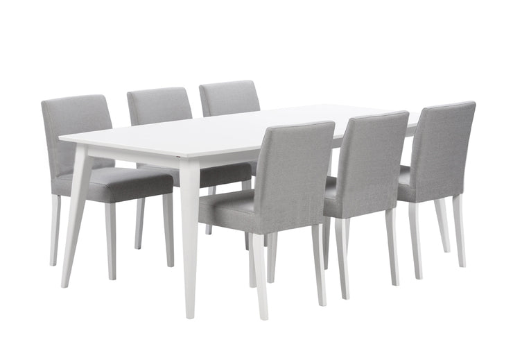 Kuvan kokonaan valkoinen Deco-ruokapöytä on koivurungolla ja mdf-kannella. Kuvassa on harmaalla Mystic-kankaalla verhoillut Deco Lux -tuolit.