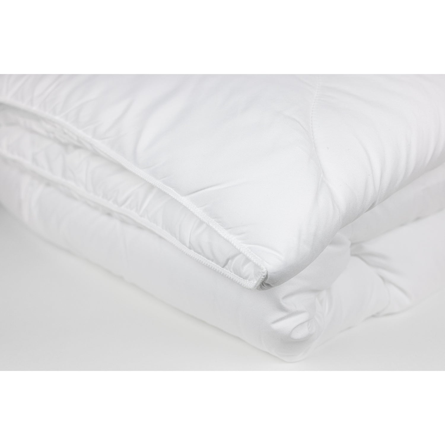 Lähikuvassa näkyy Stemma Plus -peitteen reunaommel. Sekä tuotepakkauksen peite että tyyny ovat konepestäviä ja voidaan pestä 60°C asteessa.