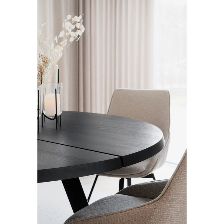 Lähikuvassa mustan pyöreän Fred-ruokapöydän saarnipuinen pinta ja beigen väriset Sierra -tuolit.