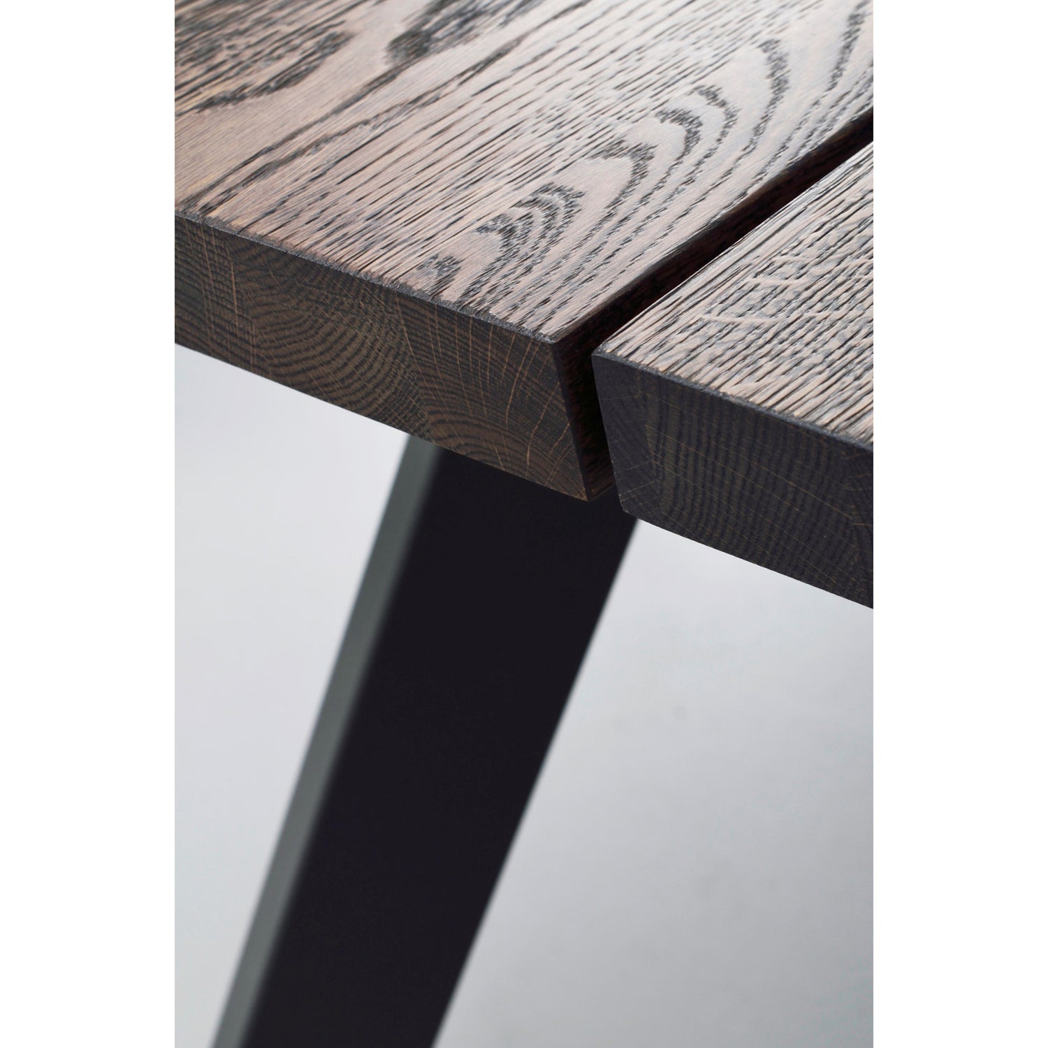 Lähikuvassa Fred-ruokapöydän 170 x 95 cm savutammenvärinen kannen pinta ja musta metallijalka.