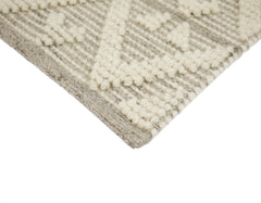 Lähikuvassa käsinkudotun Helmi-villamaton vaaleanharmaata kohokuvioitua villapintaa.