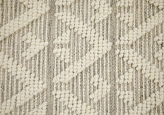 Lähikuvassa käsinkudotun Helmi-villamaton vaaleanharmaata kohokuvioitua villapintaa.