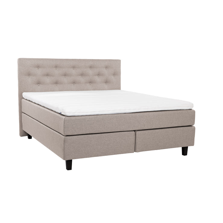 Beige Hilding Feel -jenkkisänky 160 x 200 cm hiilenmustilla 14 cm korkeilla Royal -tammijaloilla ja yhtenäisellä Hilding Hybrix Air Coolmax -sijauspatjalla. Kuvan Feel -sängynpääty myydään erikseen.