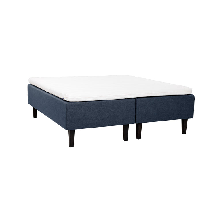 Siniset Hilding Feel -runkopatjat hiilenmustilla 23 cm korkeilla Royal -tammijaloilla ja yhtenäisellä 180 x 200 cm Hilding Hybrix Air Coolmax -sijauspatjalla.