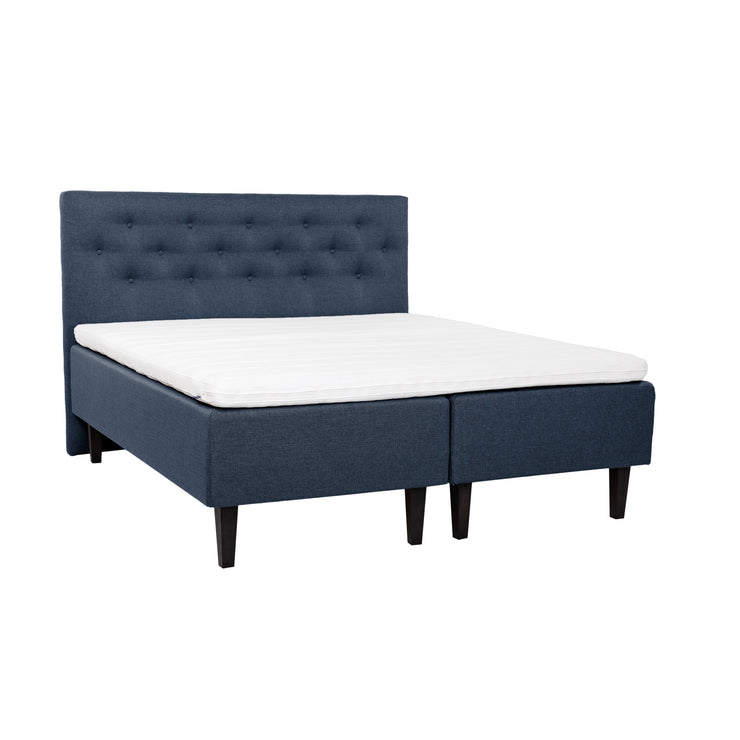 Siniset Hilding Feel -runkopatjat hiilenmustilla 23 cm korkeilla Royal -tammijaloilla ja yhtenäisellä 180 x 200 cm Hilding Hybrix Air Coolmax -sijauspatjalla. Kuvan Feel -sängynpääty myydään erikseen.