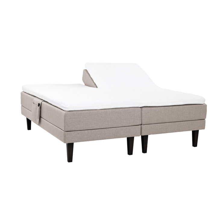 Beigen väriset Hilding Feel -moottorisängyt hiilenmustilla 23 cm korkeilla Royal -tammijaloilla ja yhtenäisellä osittain halkaistulla 160 x 200 cm Hybrix Air Coolmax Split -sijauspatjalla. Kuvan tarviketasku myydään erikseen.