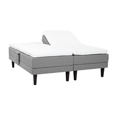 Harmaat Hilding Feel -moottorisängyt hiilenmustilla 23 cm korkeilla Royal -tammijaloilla ja erillisillä Hilding Hybrix Air Coolmax -sijauspatjoilla. Kuvan tarviketasku myydään erikseen.