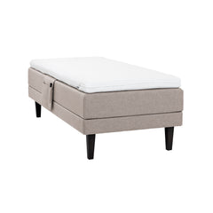 Beige Hilding Feel Ergo -moottorisänky 90 x 200 cm hiilenmustilla 23 cm korkeilla Royal -tammijaloilla ja Hilding Ergo -sijauspatjalla. Kuvan tarviketasku myydään erikseen.