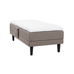 Hiekanvärinen Hilding Feel Ergo -moottorisänky 90 x 200 cm hiilenmustilla 23 cm korkeilla Royal -tammijaloilla ja Hilding Ergo -sijauspatjalla. Kuvan tarviketasku myydään erikseen.