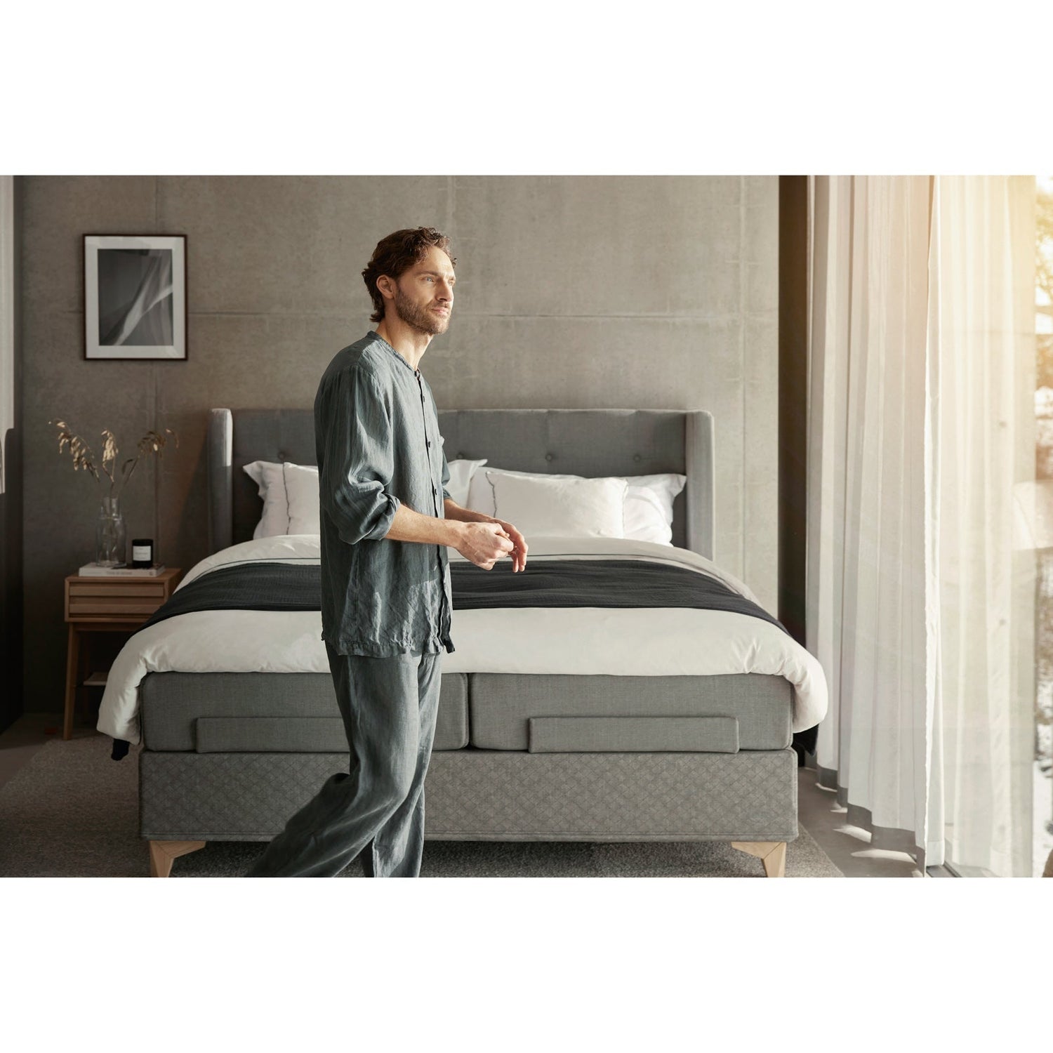 Jensen Majestic Aqtive II -moottorisänky on Nest-sängynpäädyn kanssa sisustuksellinen kokonaisuus, kuvassa on harmaa verhoiluväri ja valkotammenväriset Eicon-jalat. Jensenin sängynpääty valkotammenvärinen Eicon-yöpöytä myydään erikseen.