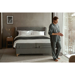 Jensen Majestic Aqtive II -moottorisänky on Nest-sängynpäädyn kanssa sisustuksellinen kokonaisuus, kuvassa on harmaa verhoiluväri ja valkotammenväriset Eicon-jalat. Jensenin sängynpääty valkotammenvärinen Eicon-yöpöytä myydään erikseen.