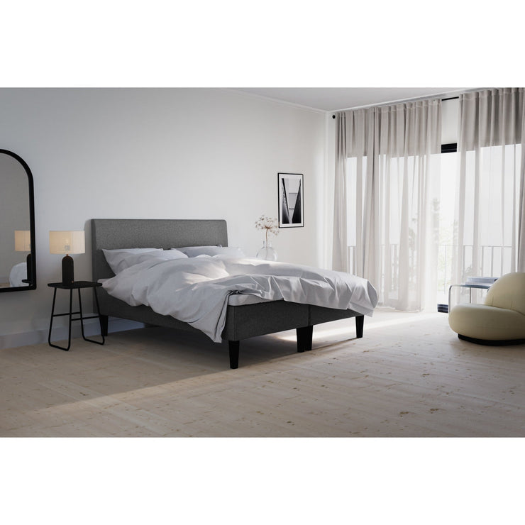 Jensen Nova Max -runkopatjasängyt sängynpäädyn kanssa ovat upea sisustuksellinen kokonaisuus. Kuvassa on tummanharmaa verhoiluväri ja nelikulmaiset 23 cm korkeat mustat tammijalat. Jensenin Lyra-sängynpääty myydään erikseen, kuten myös kuvassa oleva musta Add on Floor -yöpöytä.