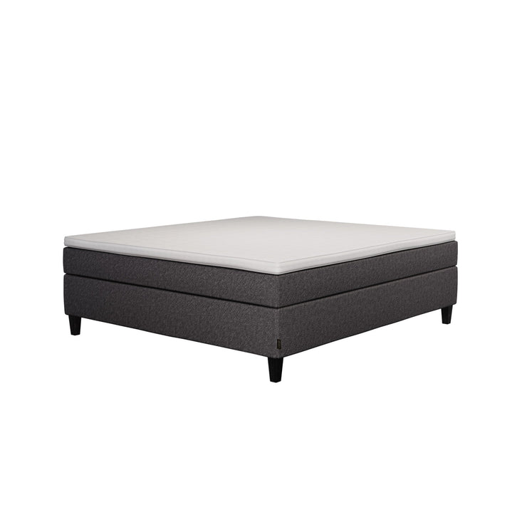 Jensen Nova Max -jenkkisängyn tummanharmaa verhoiluväri ja nelikulmaiset 14 cm korkeat mustat tammijalat. Sleep 1 -sijauspatja ja jalat sisältyvät hintaan.