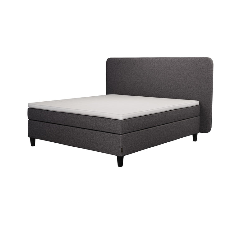 Jensen Nova Max -jenkkisängyn tummanharmaa verhoiluväri ja nelikulmaiset 14 cm korkeat mustat tammijalat. Sleep 1 -sijauspatja ja jalat sisältyvät hintaan. Jensen-sängynpääty myydään erikseen.