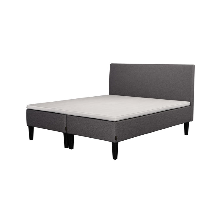 Jensen Nova Max -runkopatjat tummanharmaalla verhoiluvärillä ja nelikulmaisilla 23 cm korkeilla mustilla tammijaloilla. Yhtenäinen Sleep 1 -sijauspatja ja jalat sisältyvät hintaan. Jensenin Lyra -sängynpääty myydään erikseen.