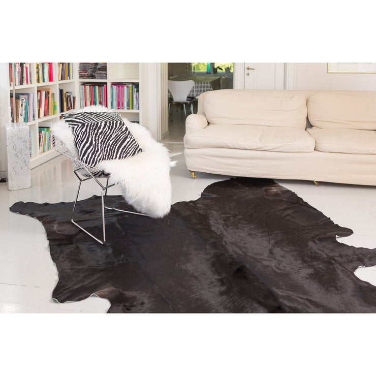 Kuvassa sisustukseen tunnelmaa ovat tuomassa Mattokympin musta häräntalja lattialla ja valkoinen erikseen myytävä lampaantalja tuolissa.