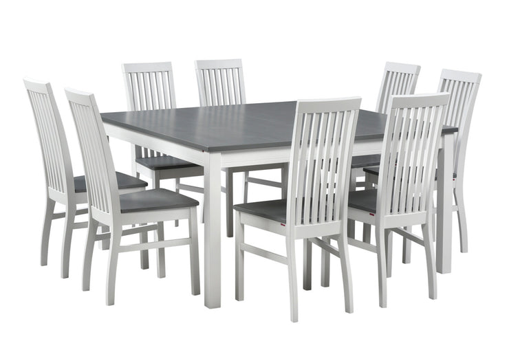 Valkoinen neliö Petra-ruokailuryhmä harmaaksi petsatuilla pöydän ja istuimien kansiosilla. Kuvassa olevat kahdeksan tuolia mahtuvat sopivasti 140 x 140 cm kokoisen pöydän ympärille.