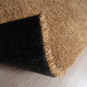 Roihu-matossa on pehmeä huopapohja, joka on helposti käsiteltävä ja sopii kaikille lattiapinnoille - myös lattialämmitteisille. Kuvassa okran värinen Roihu-matto ja sen huopapohja.