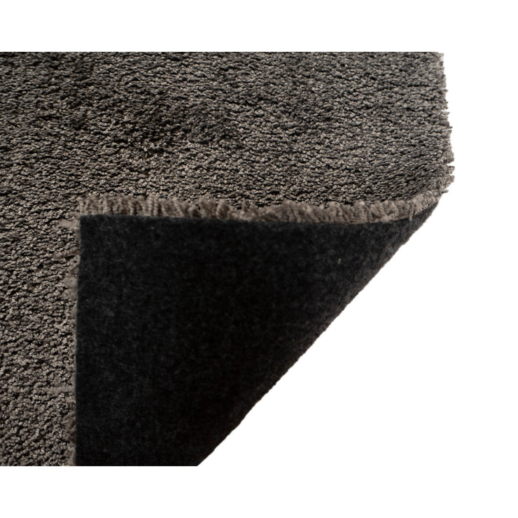 Roihu-matossa on pehmeä huopapohja, joka on helposti käsiteltävä ja sopii kaikille lattiapinnoille - myös lattialämmitteisille. Kuvassa tummanharmaa Roihu-matto ja sen huopapohja.