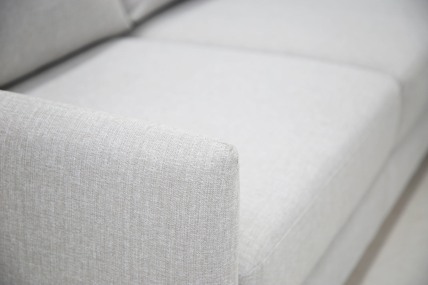 Lähikuva Stockholm-avokulmavuodesohvan vaaleanharmaalla Stark 607 -kankaalla siististi verhoillusta käsinojasta.