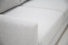 Lähikuva Stockholm-avokulmavuodesohvan vaaleanharmaalla Stark 607 -kankaalla siististi verhoillusta käsinojasta.