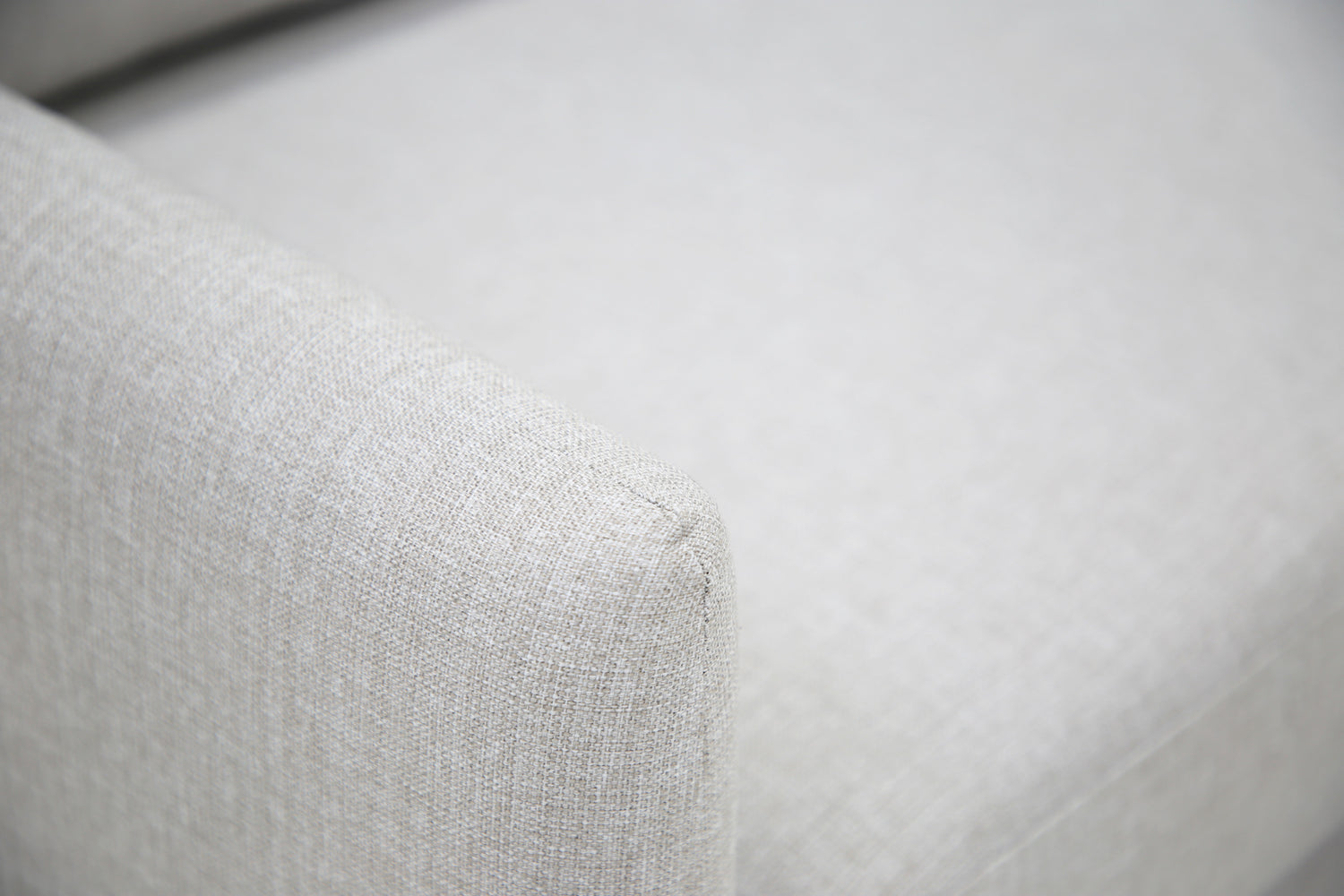 Lähikuva Stockholm-avokulmavuodesohvan vaaleanharmaalla Stark 607 -kankaalla siististi verhoillusta käsinojasta.