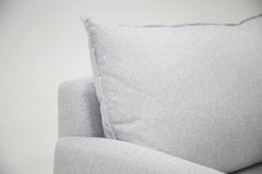 Lähikuva Stockholm-avokulmavuodesohvan vaaleanharmaasta Stark 607 -kangasverhoilusta. Selkätyynyn reunojen verhoilun viimestelevät kauniit tereet.
