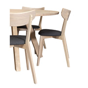 Pyöreän Swing-pöydän ruokaryhmäksi täydentävissä Rowicon Ami-tuoleissa on harmaa kangasverhoiltu istuinosa.