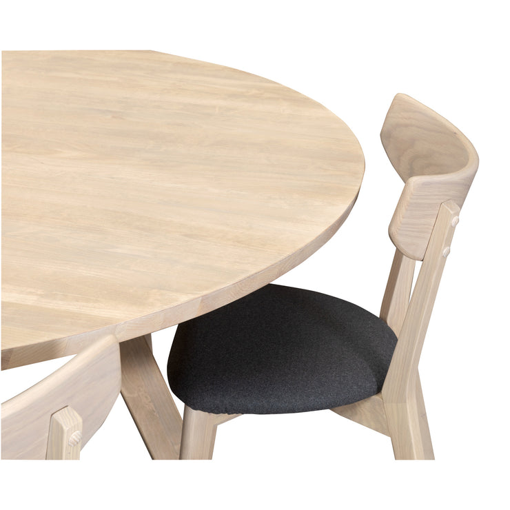 Lähikuvassa pyöreän Swing-ruokapöydän kansi ja kangasverhoiltu Rowicon Ami-tuoli.